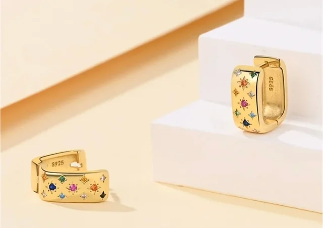 Pendientes de aro chapados en oro de 18K con circonitas multicolor sobre soporte blanco