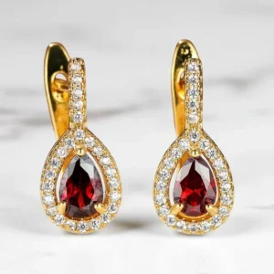 Pendientes de aro chapados en oro con piedra granate roja y circonitas blancas sobre fondo claro