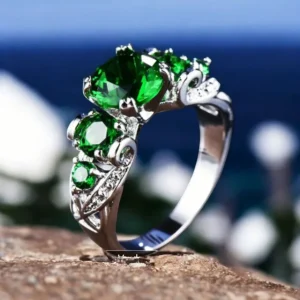 Anillo de plata con tres piedras esmeralda engastadas, diseño elegante.