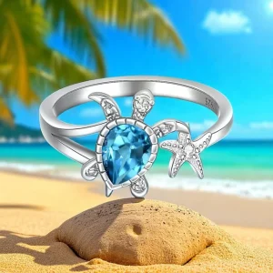 Anillo de plata con tortuga y estrella de mar sobre fondo turquesa
